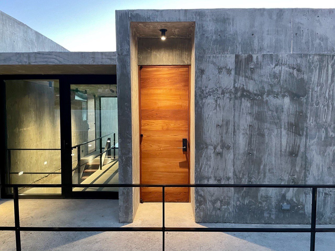 Teak entry door set in board-formed concrete